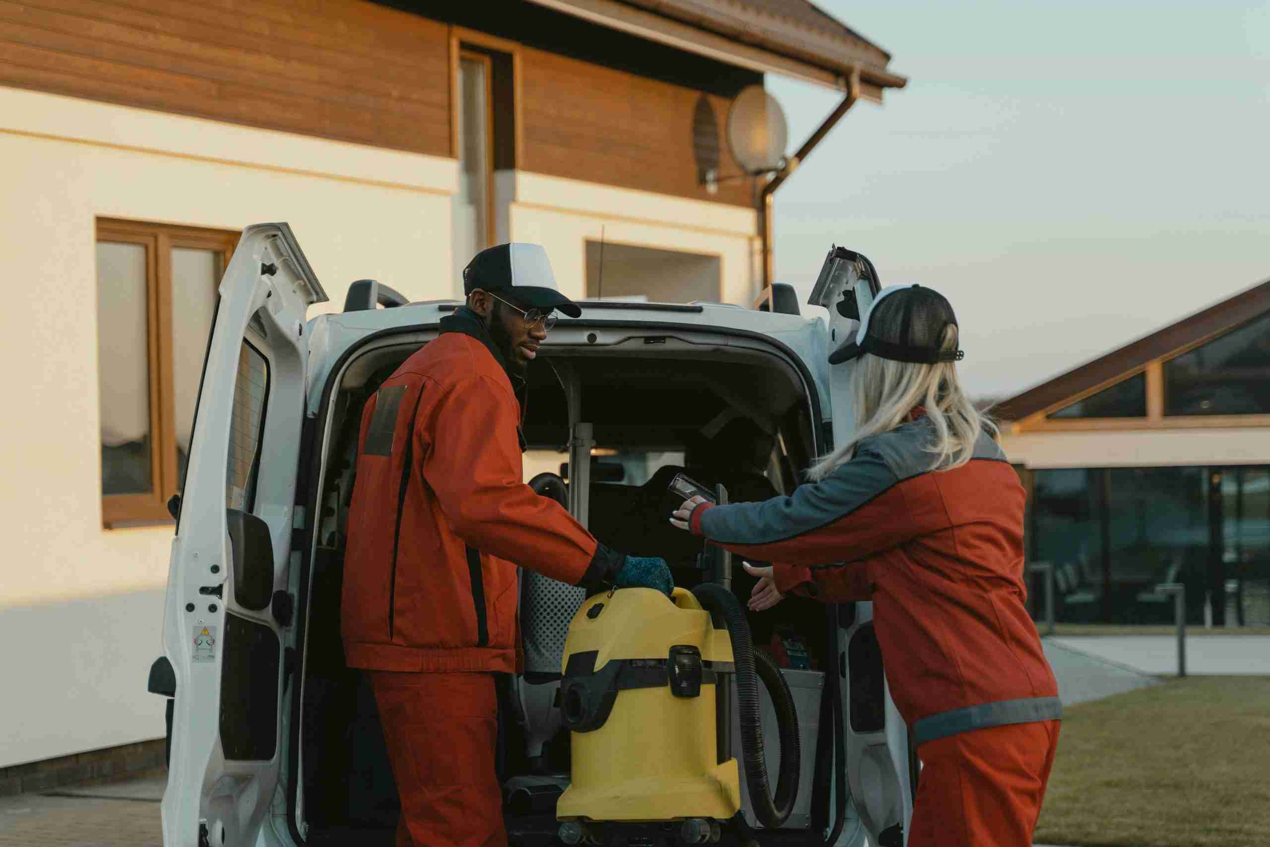 Workers loading equipment into van at sunset.