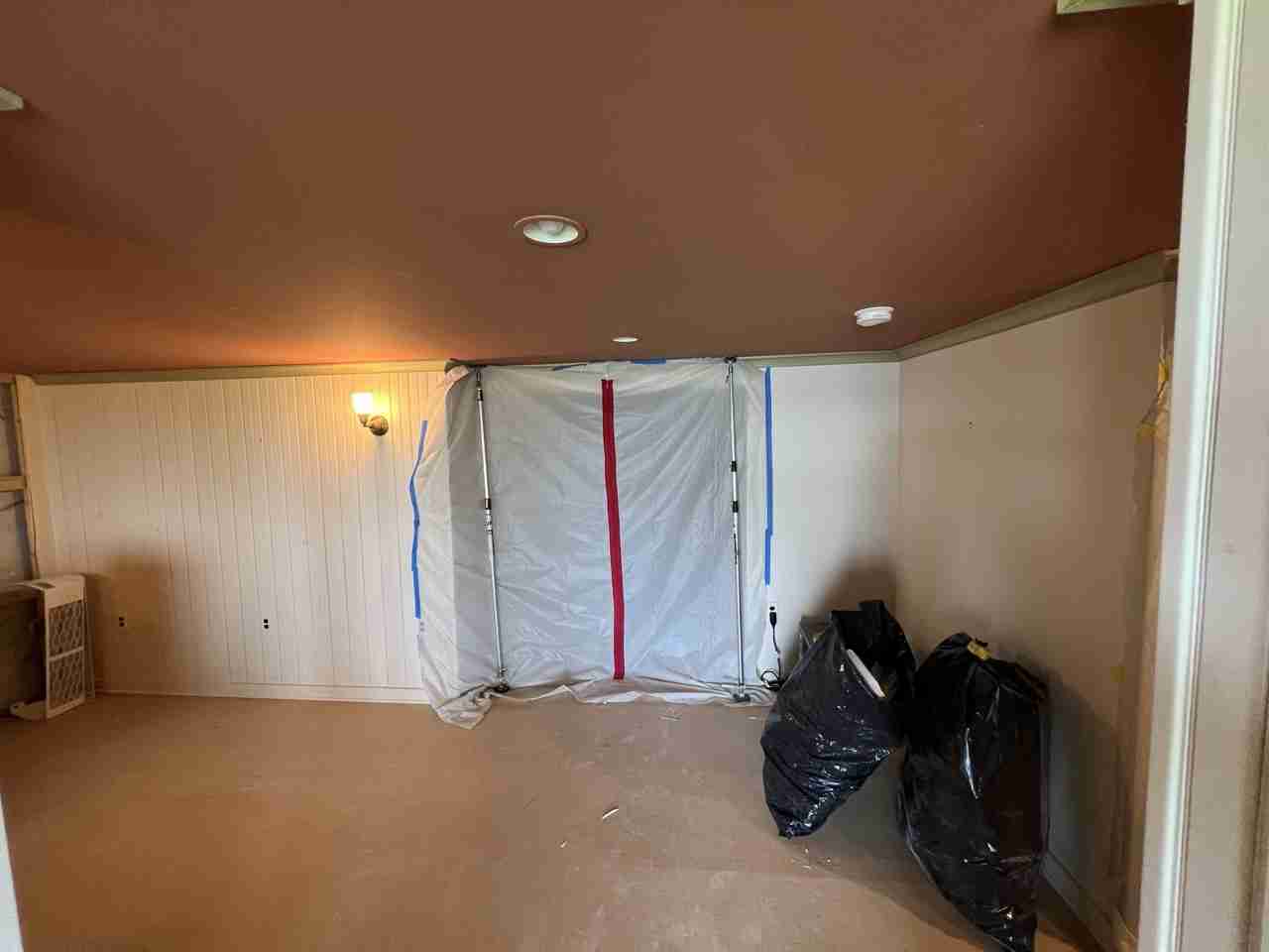 Basement remodel preparation with plastic sheeting and trash bags.