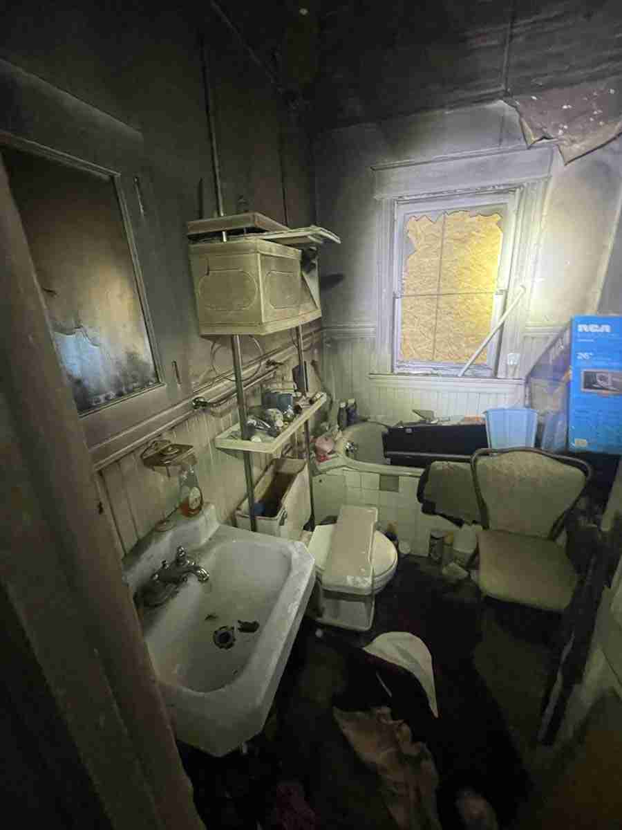 Old, cluttered bathroom with broken window and dim lighting.